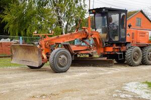 Grader on a dirt gravel road. Street repair by adding rubble. photo