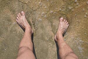 Legs men on the sea sand near sea wave photo