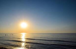 Sea sunset. People bathe in the evening at sunset in the sea. photo