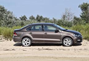 Volkswagen Polo car on the beach in the sand against a background of vegetation. photo