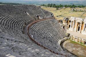 Ancient antique amphitheater in city of Hierapolis in Turkey. Steps and antique statues with columns in the amphitheater photo