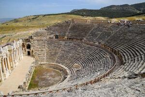 Ancient antique amphitheater in city of Hierapolis in Turkey. Steps and antique statues with columns in the amphitheater photo