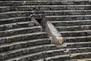 The steps of the amphitheater. Stone limestone and marble. Ancient antique amphitheater in city of Hierapolis in Turkey. Steps and antique statues with columns in the amphitheater photo