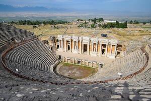 Ancient antique amphitheater in city of Hierapolis in Turkey. Steps and antique statues with columns in the amphitheater photo