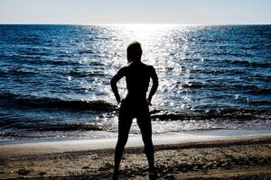 Silhouette of a beautiful girl figure on the background of the sea at sunset photo