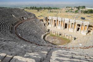 Ancient antique amphitheater in city of Hierapolis in Turkey. Steps and antique statues with columns in the amphitheater photo