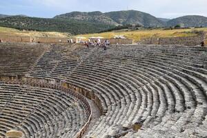 Ancient antique amphitheater in city of Hierapolis in Turkey. Steps and antique statues with columns in the amphitheater photo