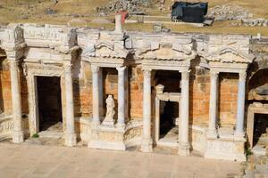Ancient antique amphitheater in city of Hierapolis in Turkey. Steps and antique statues with columns in the amphitheater photo