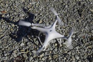 Drone Phantom 4 stands on the gravel and turns the propellers. Preparation for flight of the drone. photo