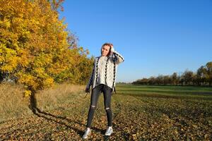 Girl on a background of yellow leaves of autumn trees. Autumn photo session.