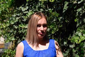 Portrait of a girl in a blue dress on background of green arbor of ivy. photo