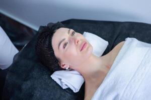 Young beautiful woman getting facial treatment in spa salon. Beauty treatment concept. photo