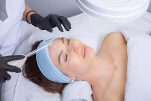 Young beautiful woman getting facial treatment in spa salon. Beauty treatment concept. photo