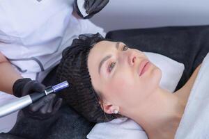 Young beautiful woman getting facial treatment in spa salon. Beauty treatment concept. photo