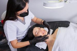 Young beautiful woman getting facial treatment in spa salon. Beauty treatment concept. photo