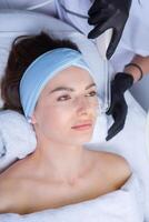 Young beautiful woman getting facial treatment in spa salon. Beauty treatment concept. photo