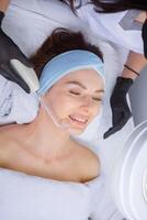 Young beautiful woman getting facial treatment in spa salon. Beauty treatment concept. photo