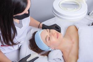 Young beautiful woman getting facial treatment in spa salon. Beauty treatment concept. photo