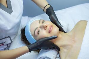 Young beautiful woman getting facial treatment in spa salon. Beauty treatment concept. photo