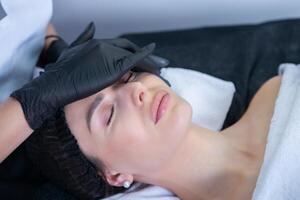 Young beautiful woman getting facial treatment in spa salon. Beauty treatment concept. photo
