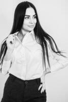 business woman with long brunette hair in white shirt and black skirt on grey background. Black and white portrait of beautiful young brunette photo