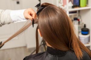 profesional peluquero corte pelo de joven mujer en belleza salón foto