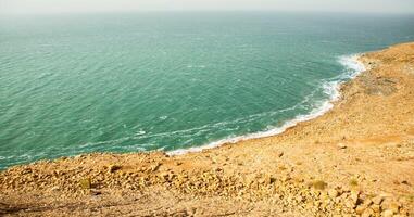 ver de muerto mar línea costera a puesta de sol hora en Jordán. sal cristales a puesta de sol. muerto mar paisaje con mineral estructuras foto