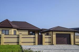 Brick house with a fence and gates. View of a new built-up fence and a house made of bricks and corrugated metal. photo