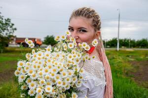 joven niña con un ramo de flores de margaritas en campo. margaritas en un amapola campo. foto