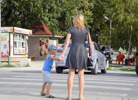 madre y hijo cruzar el la carretera en un peatonal cruce. la seguridad de tráfico foto