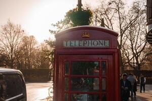 Red Festive Telephone Box Adorned with a Wreath, Winter Scene, London UK photo