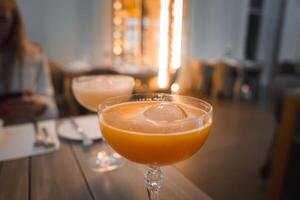 enfriado naranja cóctel en elegante vaso con acogedor comida ambiente foto