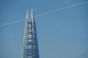 Sunlit Shard, the iconic skyscraper, stands against London's blue sky, UK. photo
