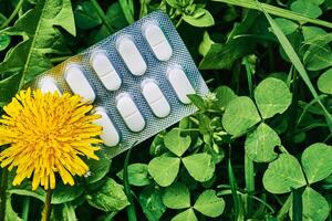 blanco pastillas en el plastico ampolla en verde césped y diente de león en prado foto