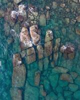 an aerial view of rocks and water in the ocean photo