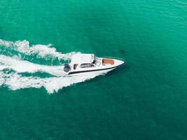 a boat traveling on the water with a white motor photo