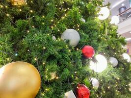 Happy new year cozy home interior with christmas tree and garlands small group white red and golden balls. blurred lights golden bokeh.Merry Christmas background. photo