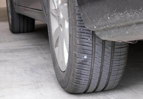 metal screws put on car tires low pressure. Closeup of car tire punctured with iron screws Tire puncture on black background with copy space. selective focus photo