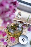 green tea in a glass teapot with a bouquet of flowers photo