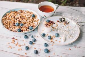 Cup of tea and granola with blueberries on wooden table photo