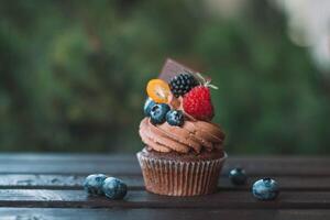 Chocolate cupcake with fresh berries on wooden table, selective focus photo