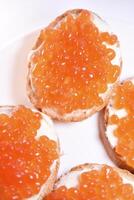 Red salmon caviar on bread and butter. A sandwich with caviar and butter on a plate. photo