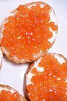 Red salmon caviar on bread and butter. A sandwich with caviar and butter on a plate. photo