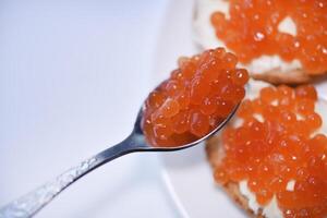 Red salmon caviar on bread and butter. A spoon with red caviar. photo