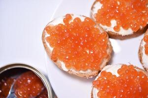 Red salmon caviar on bread and butter. A spoon with red caviar. photo