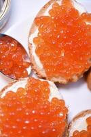 Red salmon caviar on bread and butter. A sandwich with caviar and butter on a plate. photo