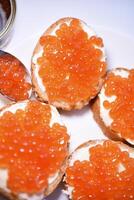 Red salmon caviar on bread and butter. A sandwich with caviar and butter on a plate. photo