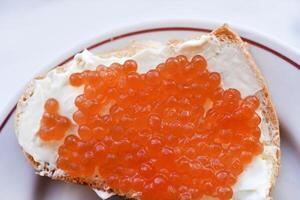 Red salmon caviar on bread and butter. A sandwich with caviar and butter on a plate. photo