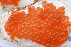 Red salmon caviar on bread and butter. A sandwich with caviar and butter on a plate. photo