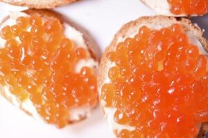 Red salmon caviar on bread and butter. A sandwich with caviar and butter on a plate. photo